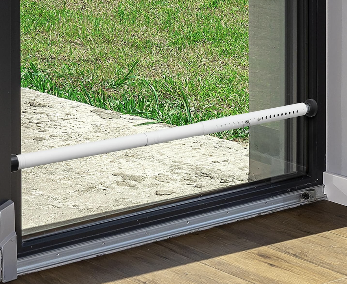A patio door with a white safety bar wedged in it.