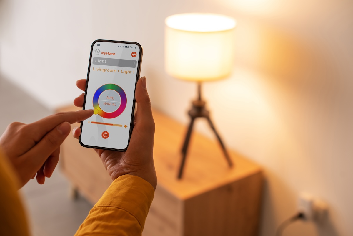A woman controls a light using a smart light feature on her phone.