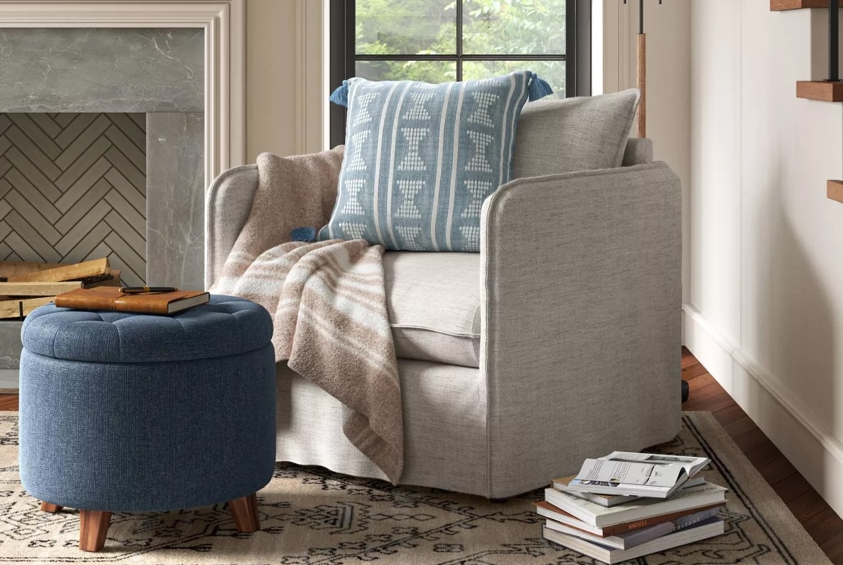 Navy round ottoman near beige comfortable chair in a rustic living room.