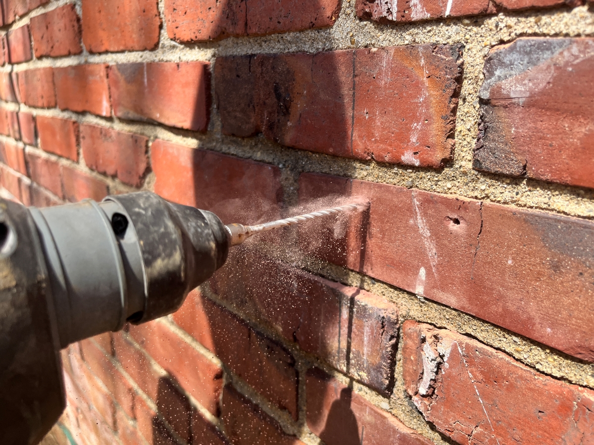 Close up of drill used to drill into brick wall.