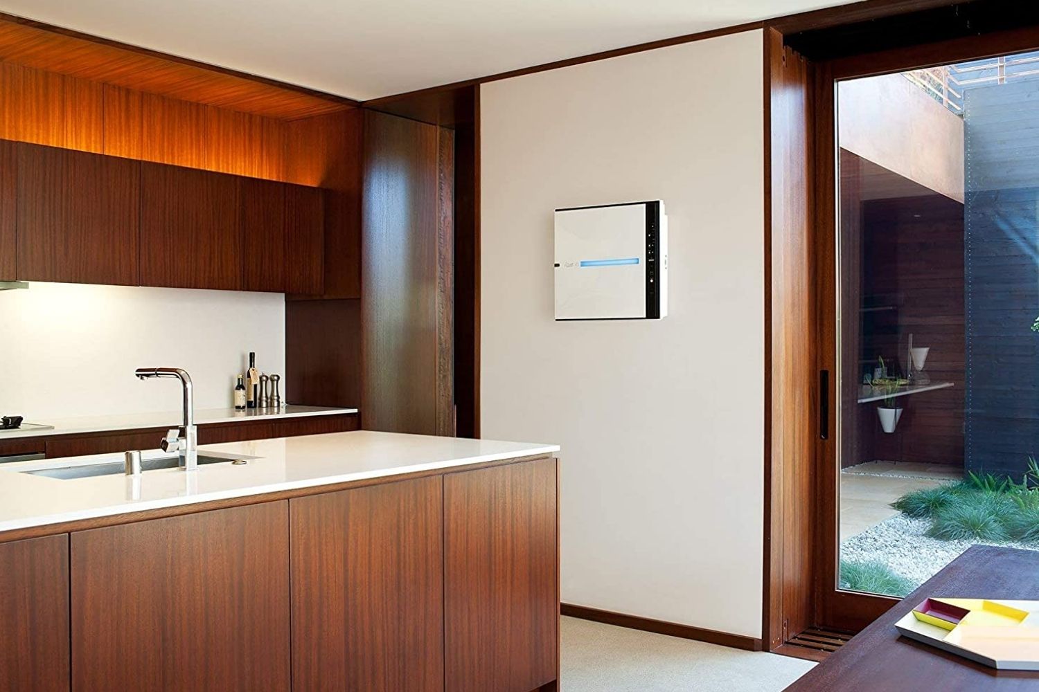 An air purifier for smoke installed in the wall in a sleek and modern kitchen.