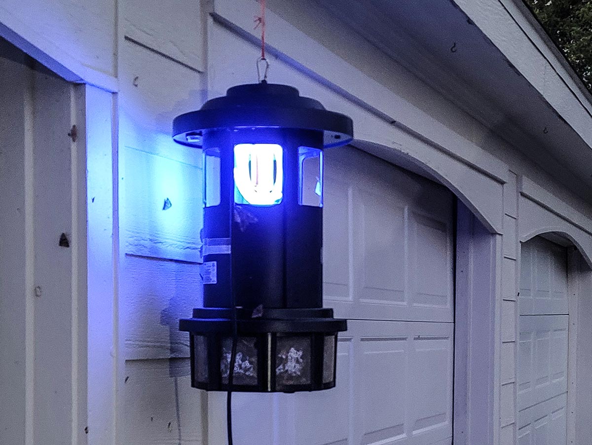 The best mosquito trap option lit up and hanging near a garage door