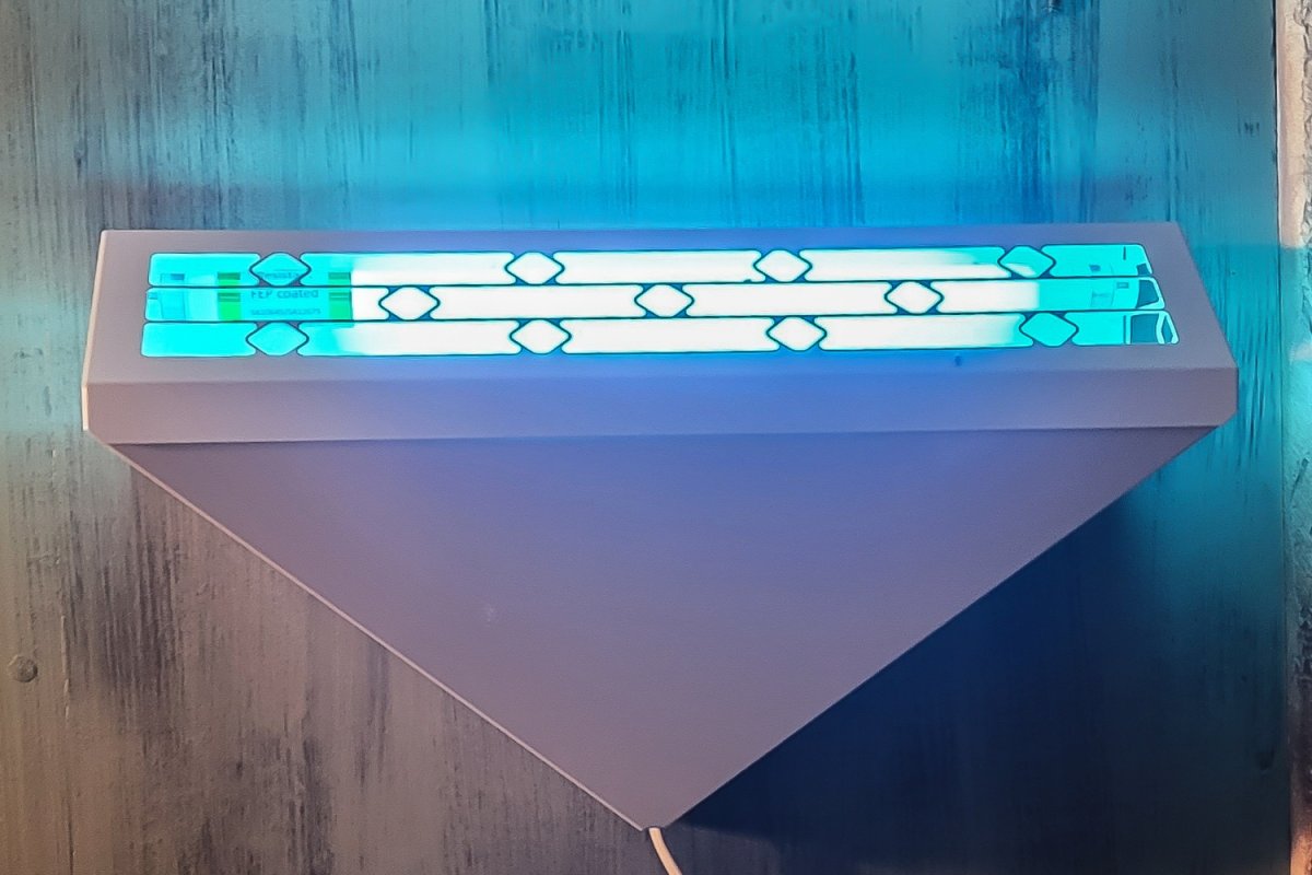 Large white triangular mosquito trap on a wall, illuminated
