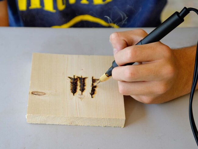 Teen using wood burning tool to draw trees