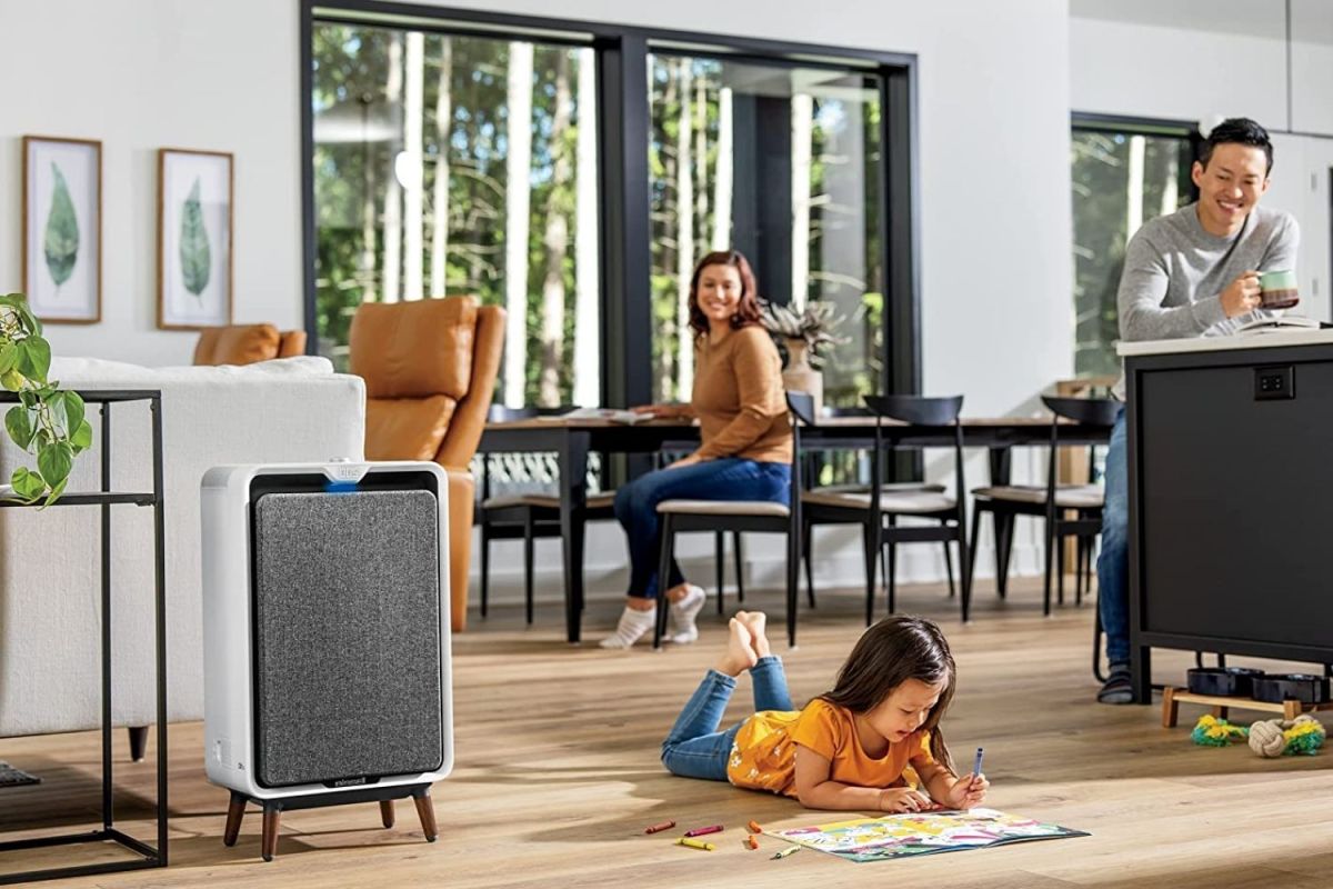 A family enjoying various spaces in their living and dining rooms while an air purifier for smoke operates in the corner.