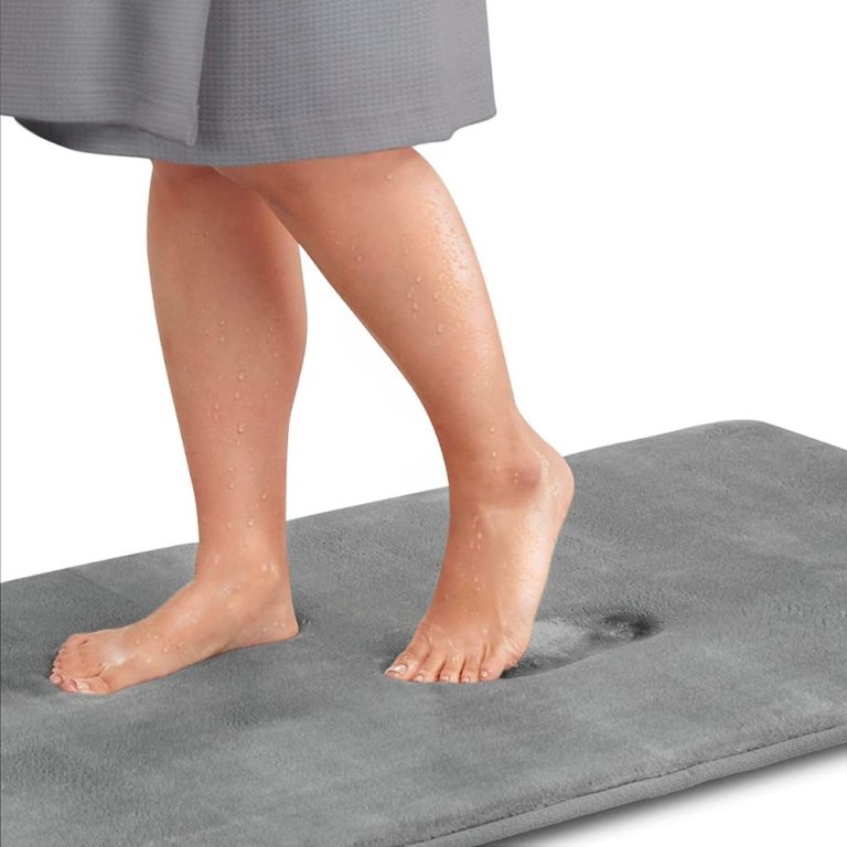 lower legs and feet stepping on Genteele Memory Foam Bath Mat, gray, on white background