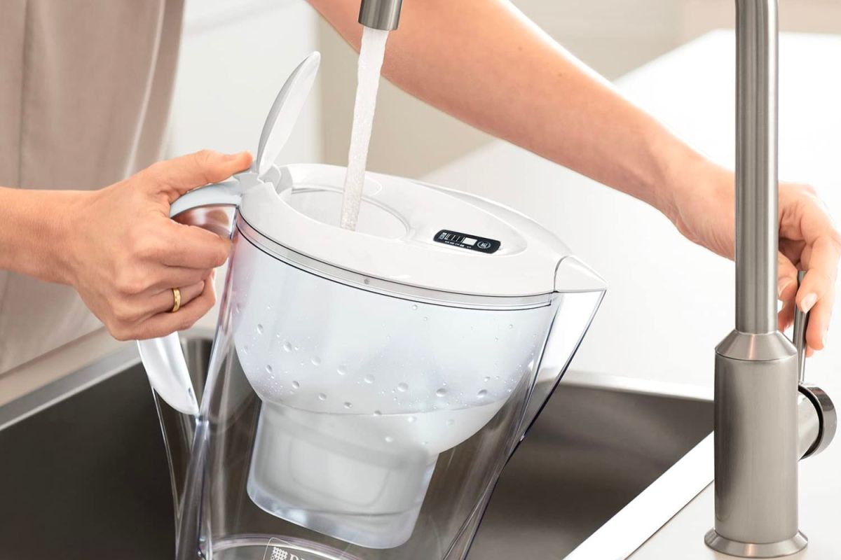 A person refills the best water filter pitcher option at the kitchen sink