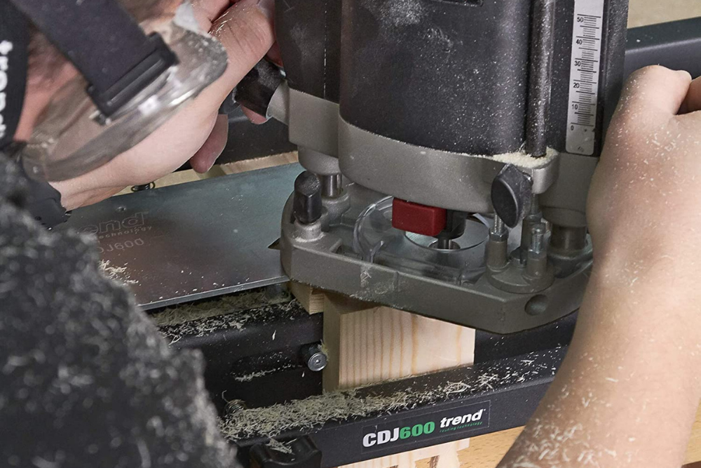 A person using the best dovetail jig to begin cutting a dovetail joint on a light piece of wood.