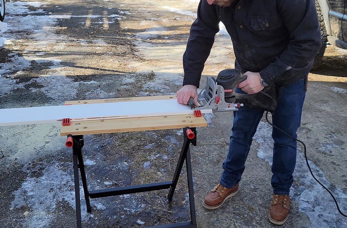 A person using a saw to cut a board that's on top of the best portable workbench.