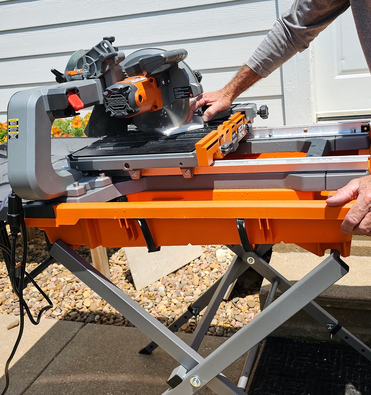 A person using the best tile saw option on a stand to cut a tile