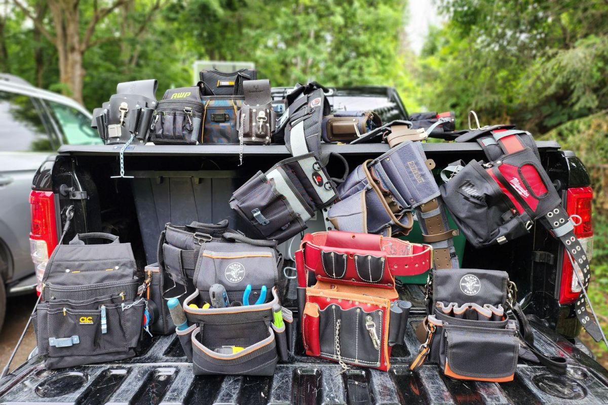 Several electrician tool belts in the back of a black truck