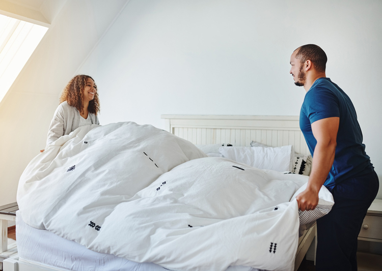 couple making bed with duvet