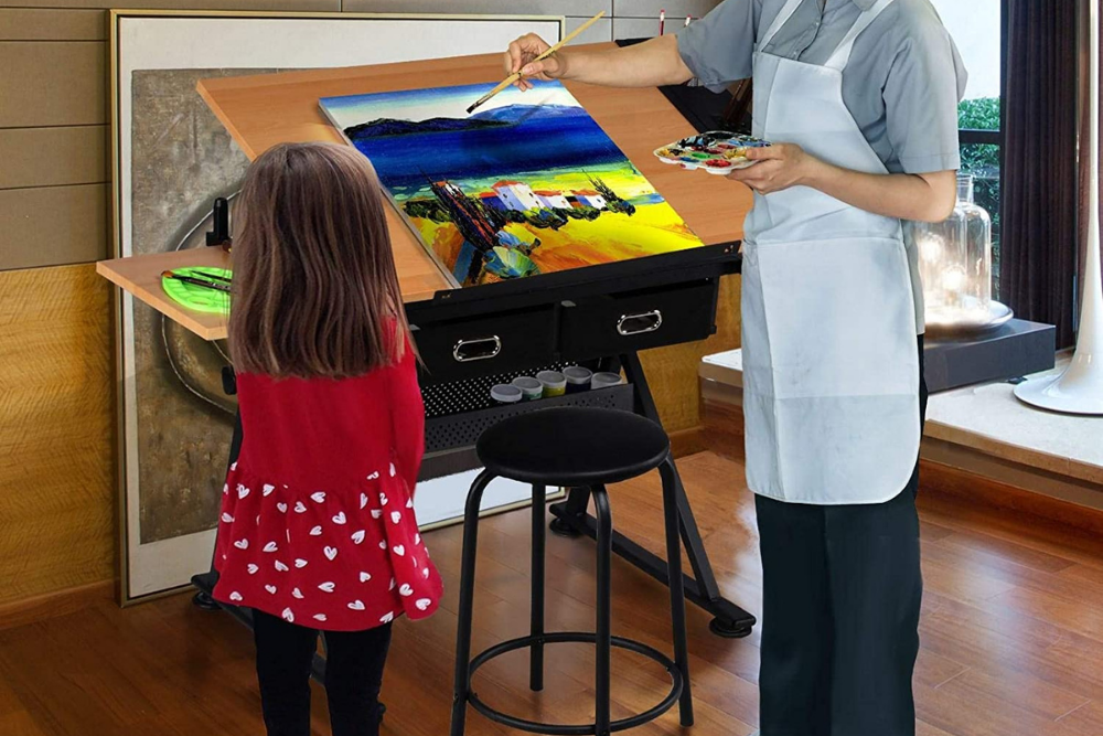 An adult and child looking at and using the best drafting table option to paint a piece of art
