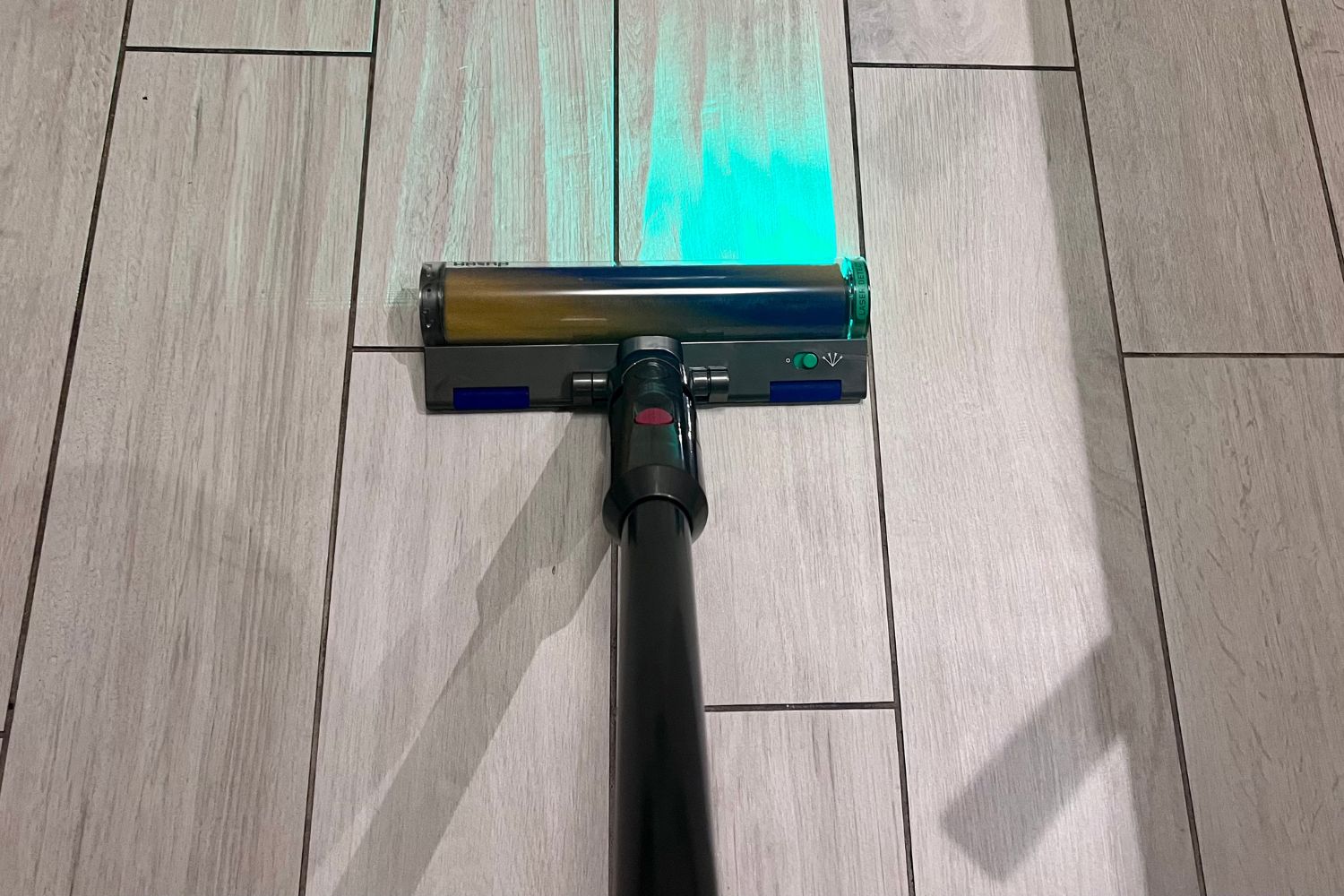 The best vacuum for tile floors in use cleaning a tile floor with its LED light shining on debris.