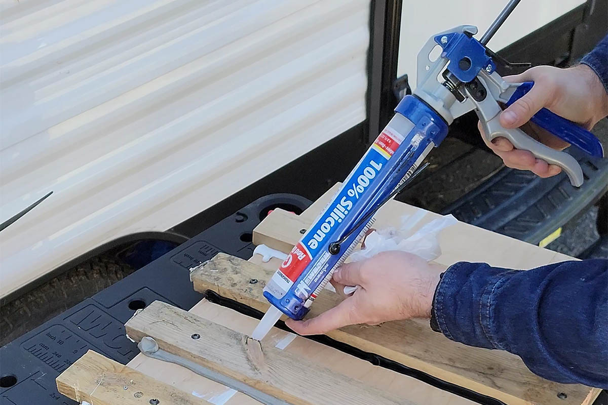 A person using the best exterior caulk to seal a piece of wood fencing.