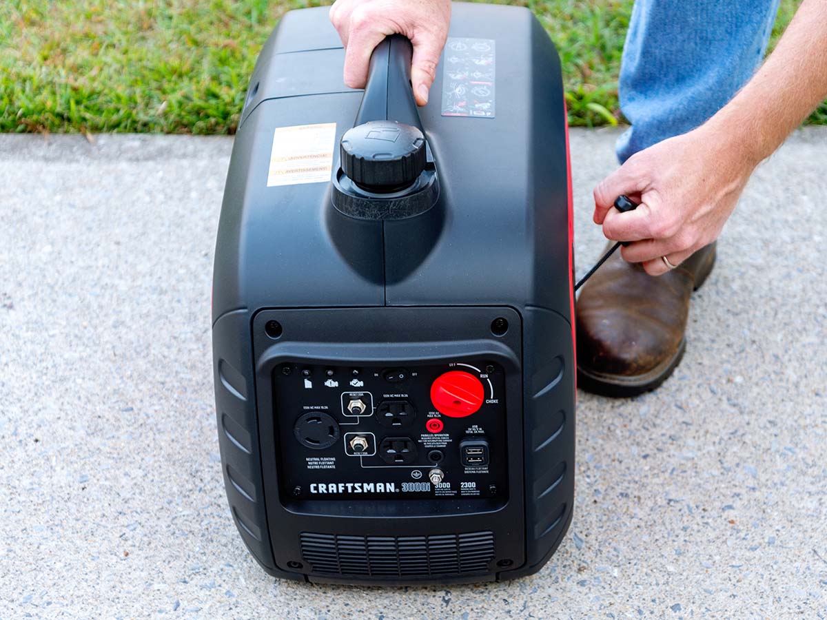 Person pulling recoil start on Craftsman generator on cement driveway