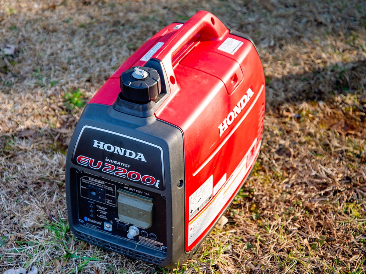 Red and black Honda EU2200i generator on grass