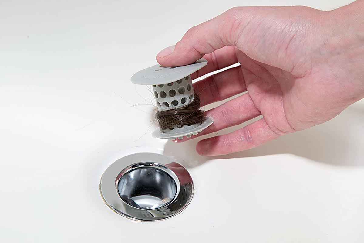 A person holds the best shower drain hair catcher option after it's been used to prevent a substantial amount of hair from going down a tub drain