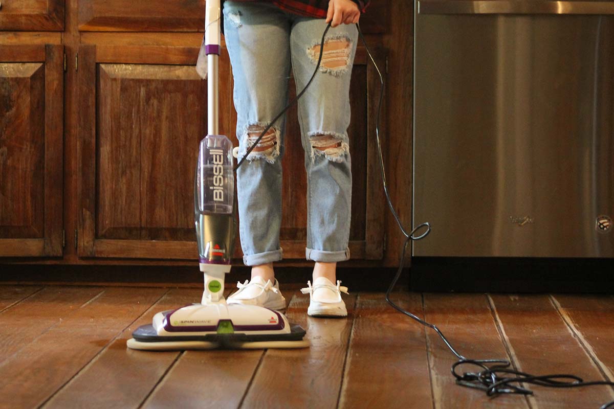 A woman using the best spin mop option to clean hardwood floors