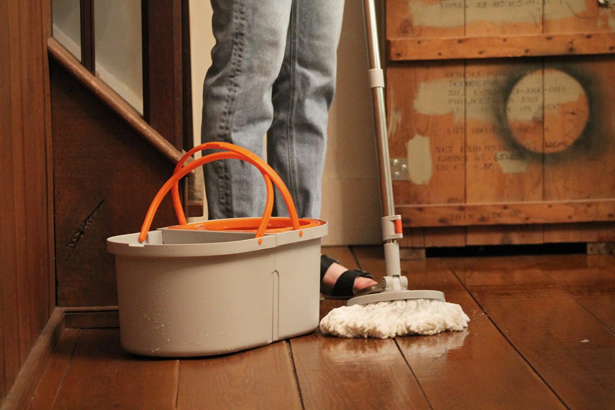 A person using the best spin mop and bucket option to clean hardwood floors