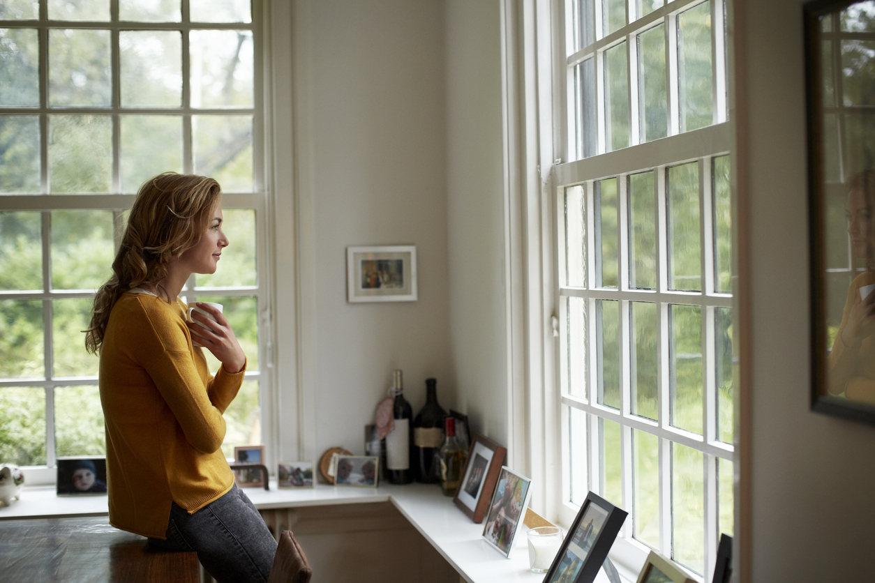 woman in kitchen looking out window at natural surroundings