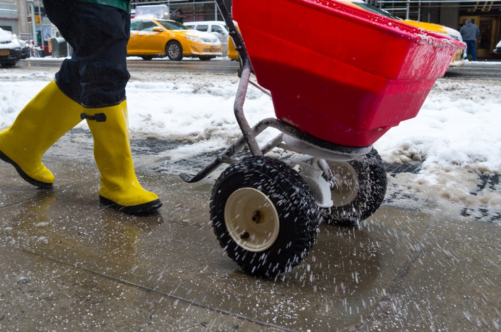 Person in yellow boots using ice melt