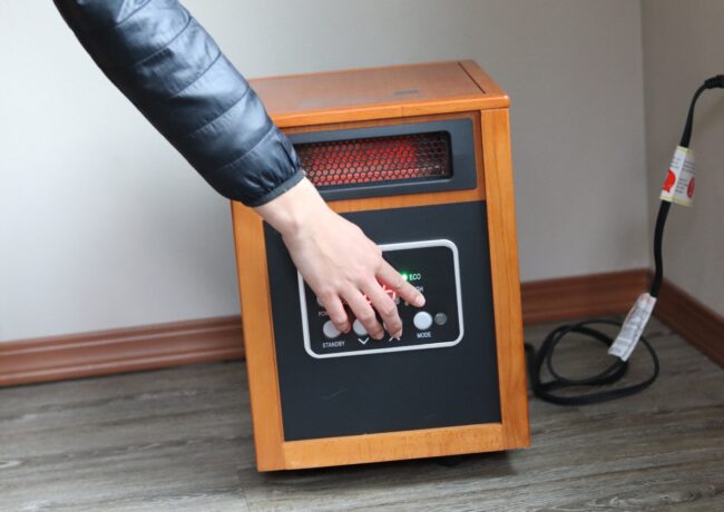 A person adjusting a space heater