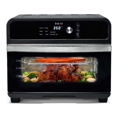 The Instant Oven 18L Air Fryer Toaster Oven cooking a whole chicken and some vegetables.