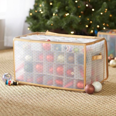 The Wayfair Basics Ornament Storage box on a carpeted floor next to a Christmas tree and full of ornaments.