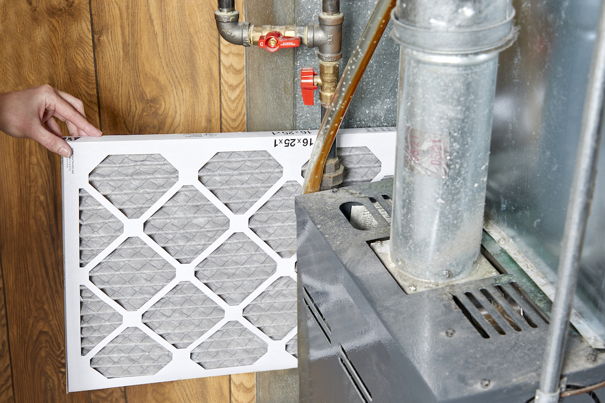 Woman inserts new filter into a furnace.
