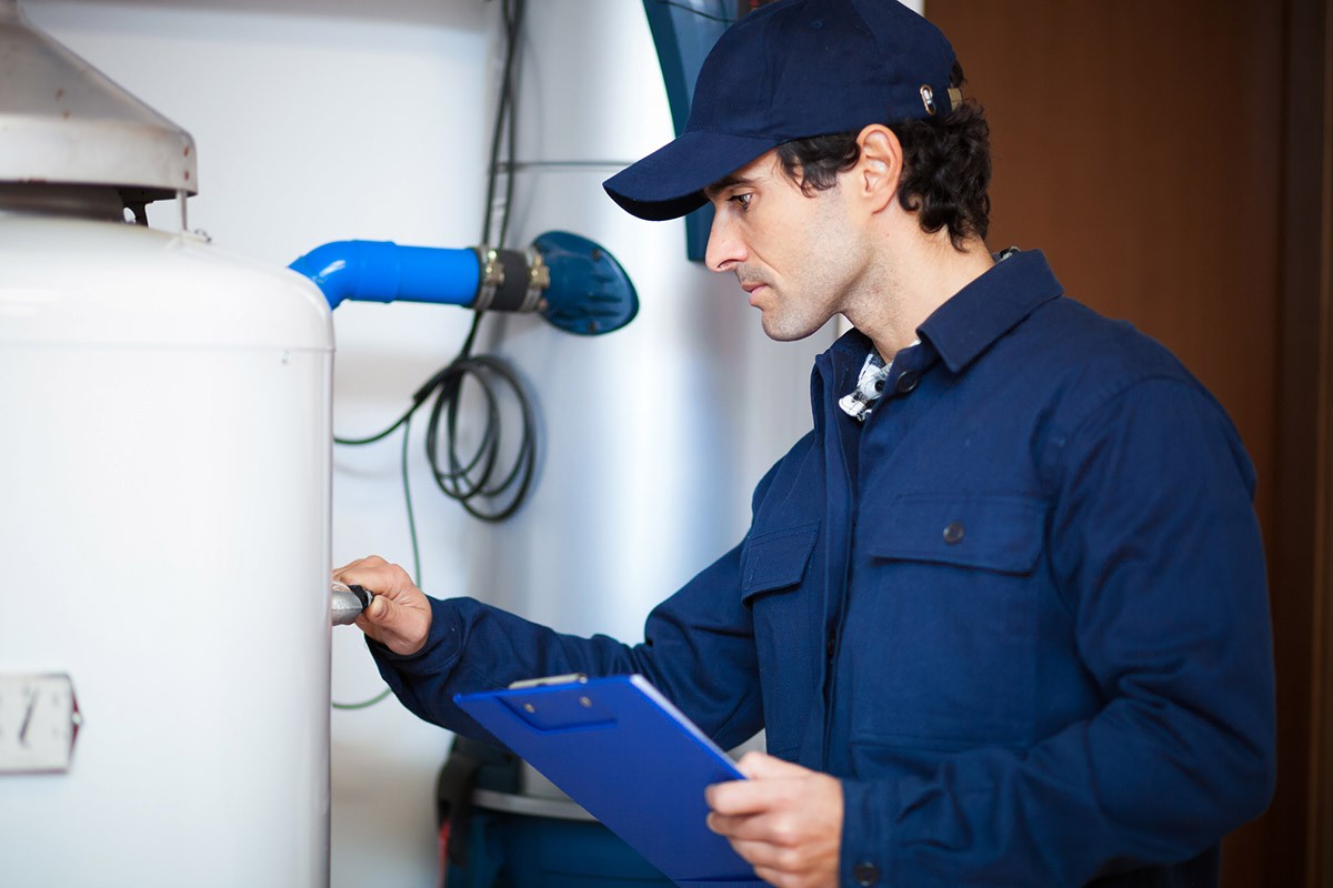 A worker adjusts a dial on a water heater.
