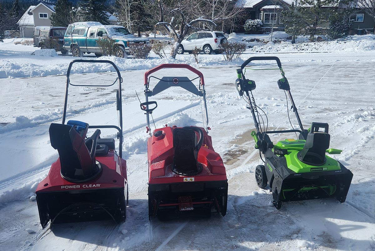 Three of the best cordless snow blowers on a snowy driveway during testing.