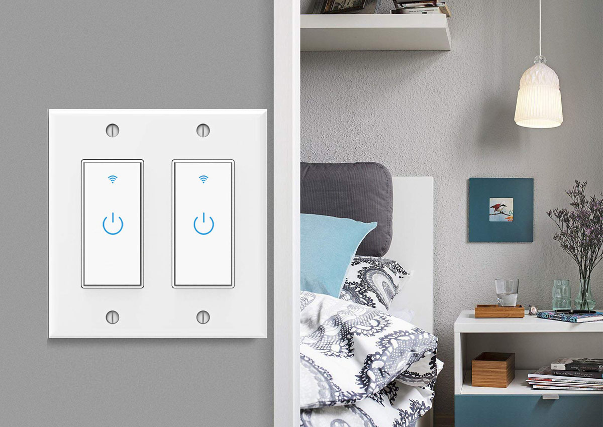 The Lesim 2 Gang Touch Wi-Fi Smart Light Switch installed on a grey wall with a blue and grey bedroom in the background.