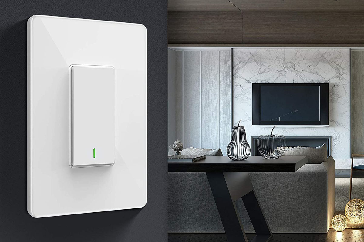 A smart switch installed on a grey wall with a contemporary living room in the background.