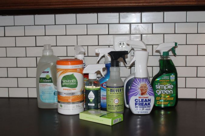 Nine all-purpose cleaners on a countertop in front of white subway tile
