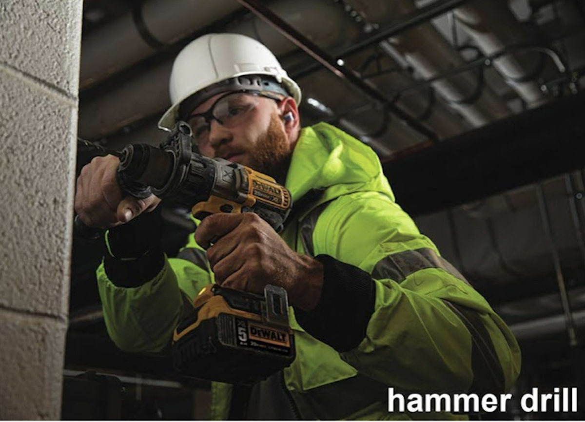 A man wearing a hard hat is using a hammer drill.