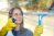 A person cleaning house windows from outside using a homemade window cleaner recipe.