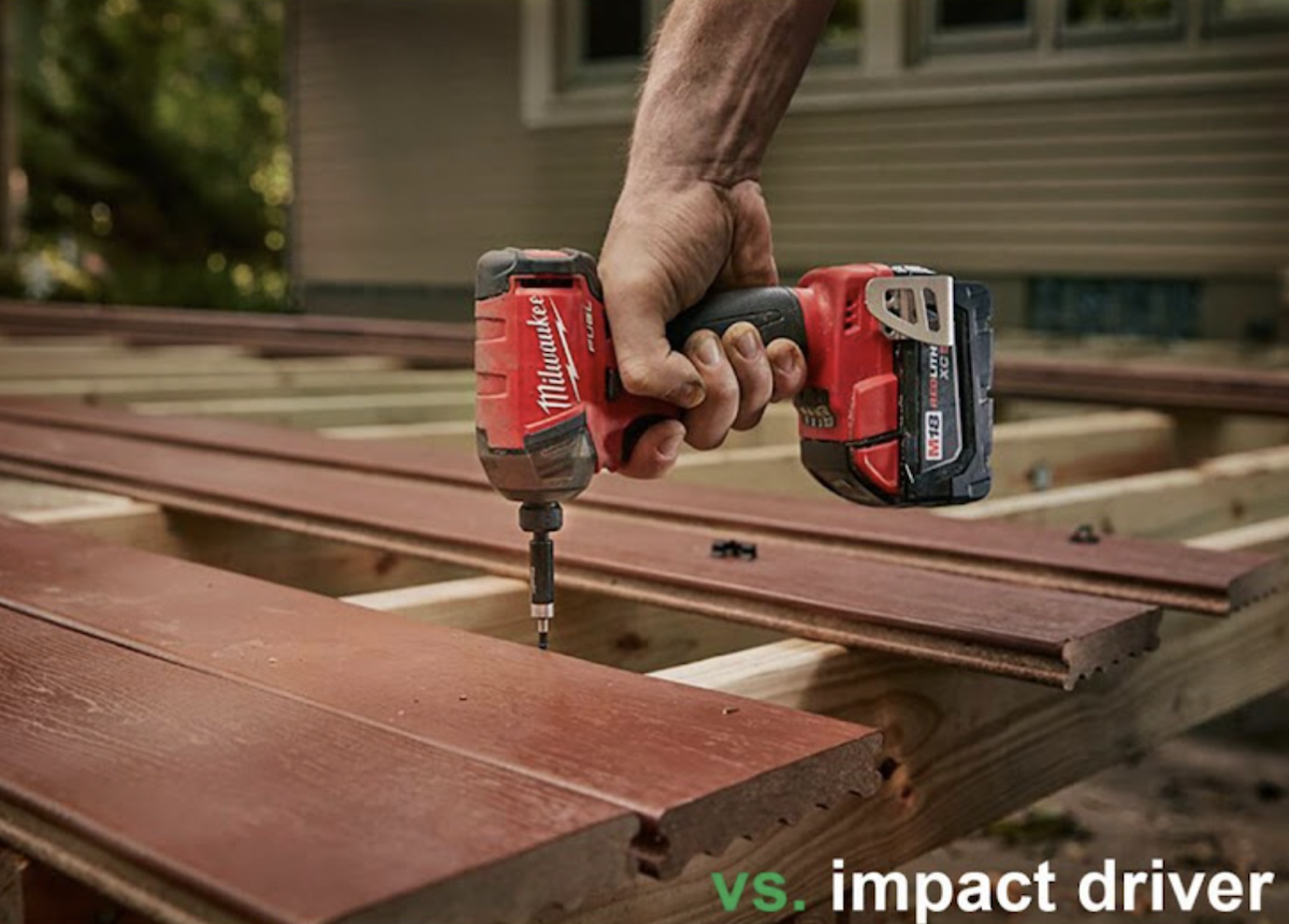 A red impact drill going into plywood.