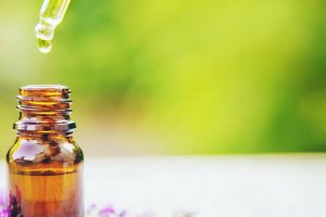 Bottle of essential oil with dropper lifted out of it.