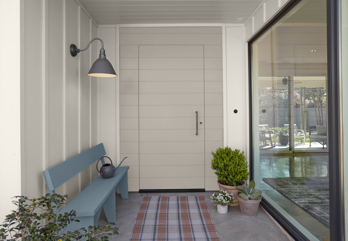 A white porch with a blue Adirondack bench.