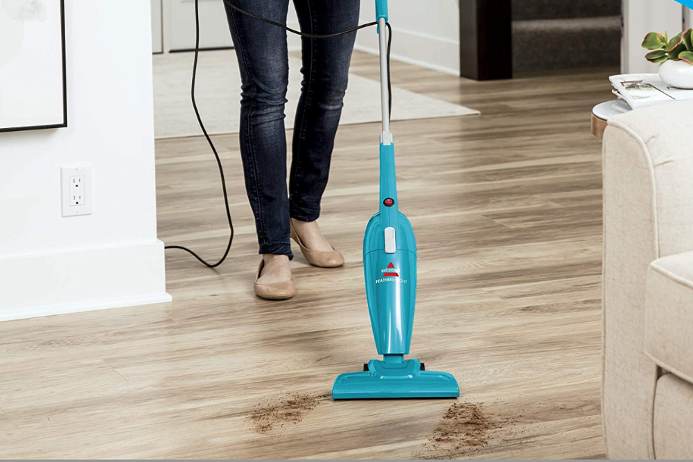 A person using the best vacuum for laminate floors to clean some dirt off a laminate floors.