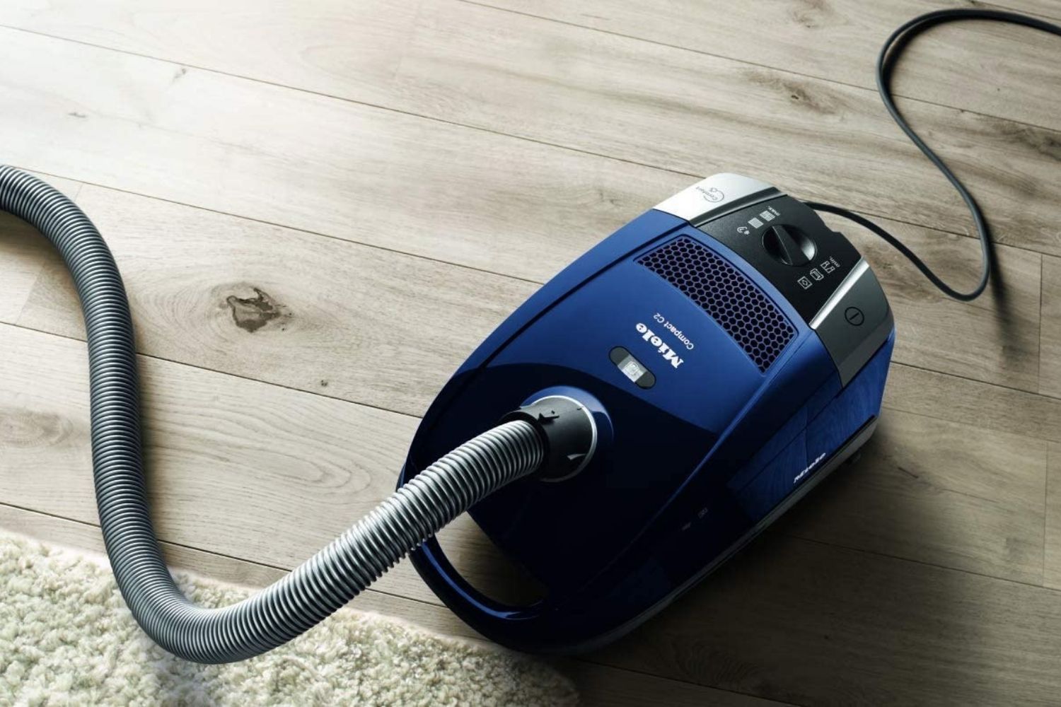The best vacuum for thick carpets sits on a wood floor next to a carpeted floor