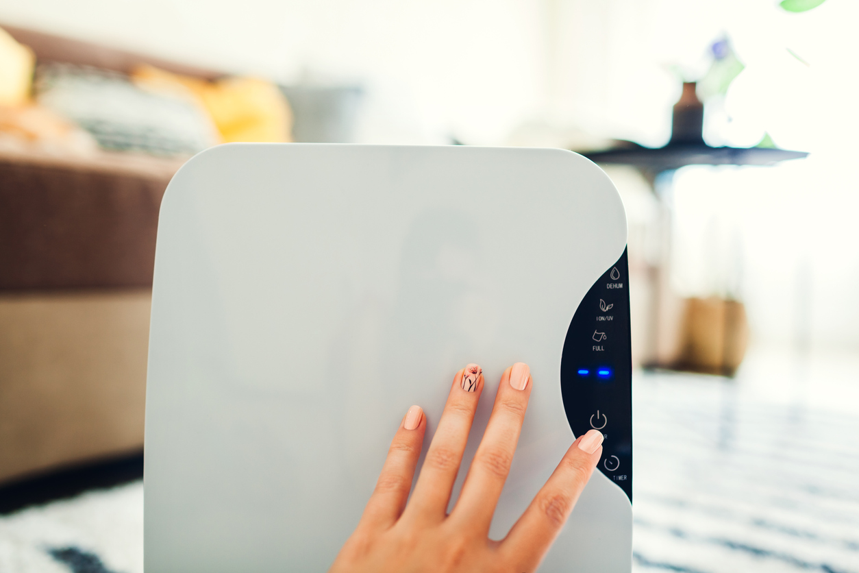 Woman adjust controls on modern dehumidifier.