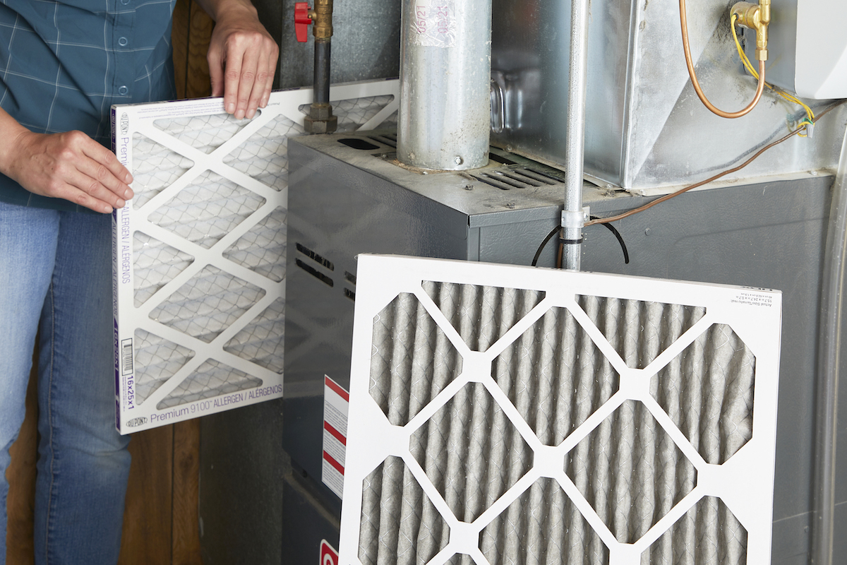 Woman inserts a new air filter after removing a dirty one, pictured in foreground.