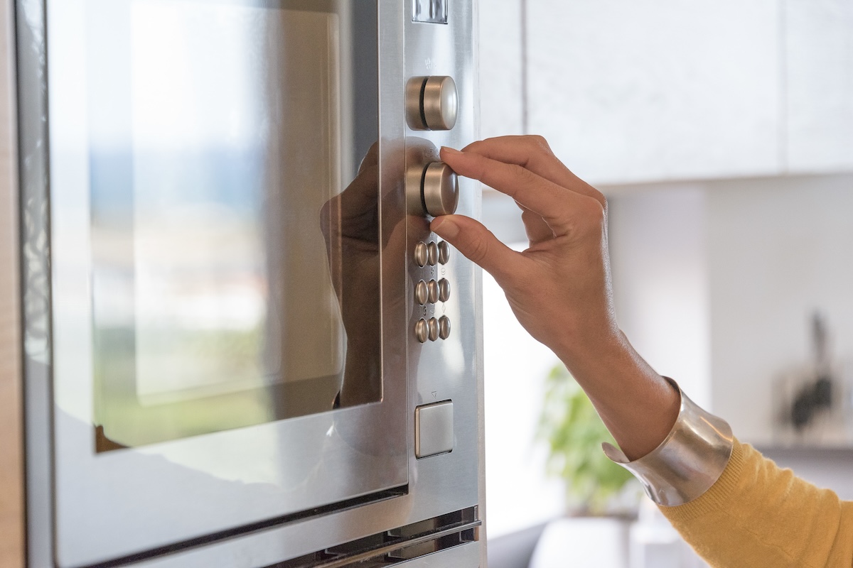 Woman with silver bracelet setting microwave time.
