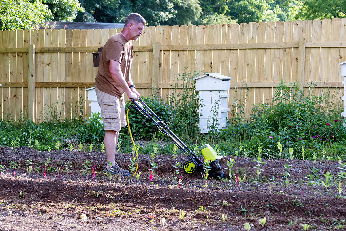 A man using the best electric tiller option in a garden