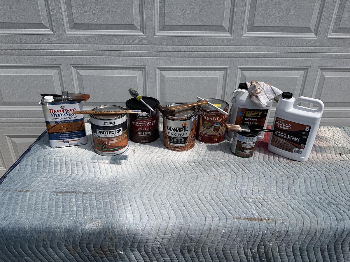 A group of the best exterior wood stains in front of a garage door before testing.
