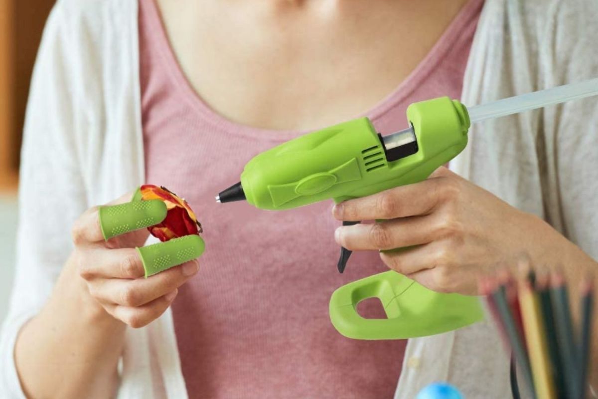 A crafter applying hot glue to a faux flower using the best cordless glue gun option