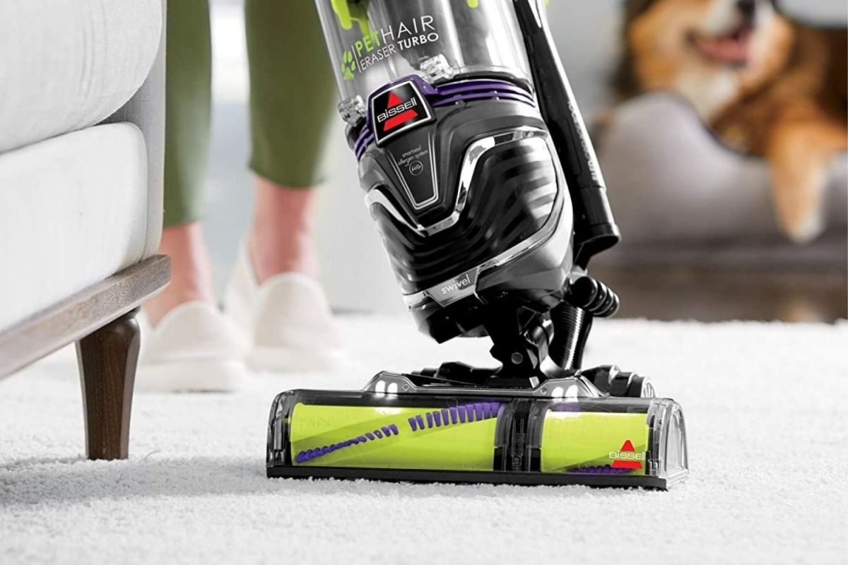 A person using the best vacuum for thick carpets option on a carpeted floor