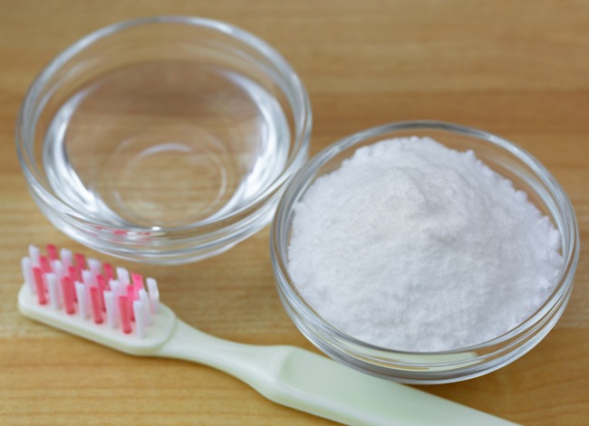 Toothbrush next to small bowls of vinegar and baking soda